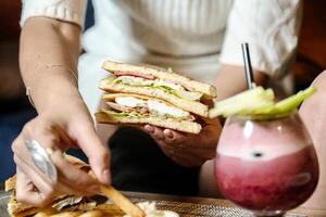 person innehav smörgås och dryck i en Kafé foto