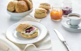 scones med grädde och frukt sylt och kopp av kaffe foto