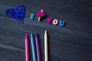 färgrik pennor, kärlek hjärta och brev på en blå trä- bakgrund. foto