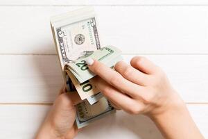 topp se av en affärskvinnas händer räkning annorlunda dollar sedlar på trä- bakgrund. Framgång och rikedom begrepp foto