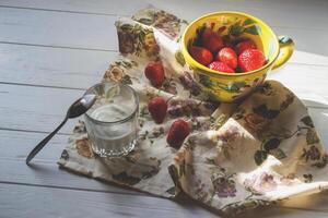 en råna av mogen jordgubbar och glas av grädde på en vit trä- tabell. de friska mat. foto