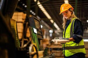 fabrik ingenjör kvinna stående självsäker till kontrollera panel växla. arbetstagare Arbetar på tung maskin på industri fabrik. arbetstagare kontroll timmer av rå trä material. smart industri arbetstagare fungerar. foto