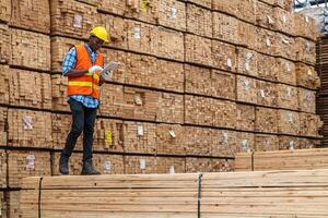 afrikansk arbetare man teknik gående och inspekterande med arbetssätt svit klänning och hand handske i timmer trä lager. begrepp av smart industri arbetstagare fungerar. trä fabriker producera trä gom. foto