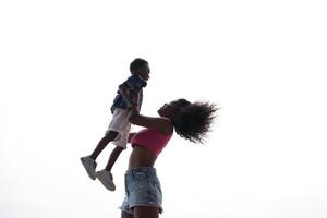 blandad lopp afrikansk och asiatisk mor och pojke är spelar på de utomhus- område. leende Lycklig familj ha roligt löpning på de strand. porträtt av mamma och unge livsstil med en unik frisyr. foto