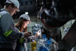 ingenjörer kolla upp kontrollera tung maskin robot ärm. olika team av industriell robotik ingenjörer samlade in runt om maskin. professionell maskineri operatörer reparera elektrisk robot på ljus digital panel. foto