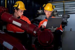 grupp av manlig ingenjör arbetare underhåll automatisk robot ärm maskin i en mörk rum fabrik. arbetstagare kontroll och reparation automatisk robot hand maskin. arbetstagare bär säkerhet glasögon och hjälm. foto