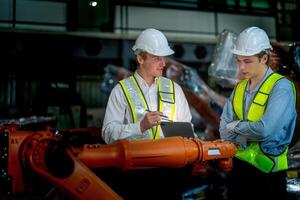 försäljning chef och fabrik ägare i kostymer förhandlings försäljning robotar Begagnade i de fabrik. företag ingenjörer möte och kontroll ny maskin robot. arbetare gående på lager svetsning maskin. foto