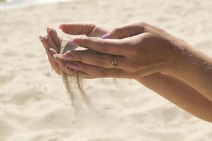de sand är häller från kvinnas händer. foto