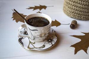 en kopp av kaffe på en vit trä- tabell, och dekoration förbi ek höst löv. foto