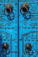 en blå dörr med svart dubbar och sten prydnad på dörröppning i tunisien foto