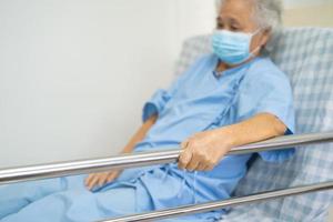 asiatisk senior eller äldre gammal kvinnapatient ligga ner hantera räcksängen med hopp på en säng på sjukhuset. foto