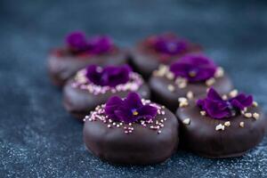 choklad tryffel med violett blommor på en mörk bakgrund. foto