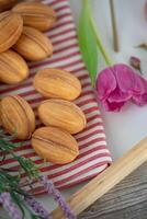 bakad mandlar i en trä- bricka på en servett med lila tulpaner foto
