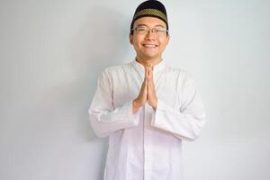 asiatisk muslim man bär glasögon och vit trasa leende håller på med hälsning utgör för Ramadhan och eid al fitr. isolerat vit bakgrund foto