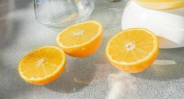 solbelyst citrus- glädje. nyligen skära apelsiner bredvid en glas juicepress foto