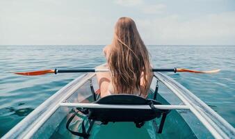 kvinna i kajak tillbaka se. Lycklig ung kvinna med lång hår flytande i transparent kajak på de kristall klar hav. sommar Semester semester och glad kvinna människor avkopplande har roligt på de båt foto