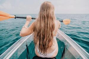 kvinna i kajak tillbaka se. Lycklig ung kvinna med lång hår flytande i transparent kajak på de kristall klar hav. sommar Semester semester och glad kvinna människor avkopplande har roligt på de båt foto