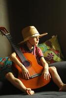 porträtt av en caucasian pojke bär en sugrör hatt och spelar de gitarr foto