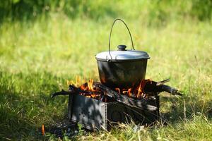 kittel med en galge på ett öppen brand utomhus. picknick camping begrepp foto