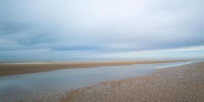panorama se de kust på låg tidvatten med strand i de tidigt morgon- foto