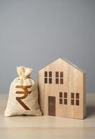 trä- hus figur och indisk rupee pengar väska. skatter. fast egendom värde värdering. göra en handla. fast egendom försäkring. hus priser. uppköp och försäljning verklig egendom. foto