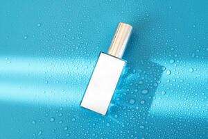 parfym flaska med falsk upp på blå bakgrund med hård ljus och vatten droppar. med skuggor platt lägga, topp se foto