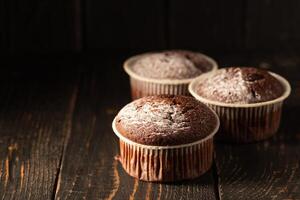 choklad muffins med pulveriserad socker på en svart bakgrund. fortfarande liv stänga upp. mörk lynnig. mat Foto. foto