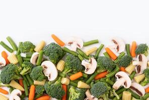 de blanda rå grönsak. platt lägga av färsk rå organisk grönsaker på vit bakgrund - broccoli, morot, svamp, grön bönor, blomkål, mini majs foto
