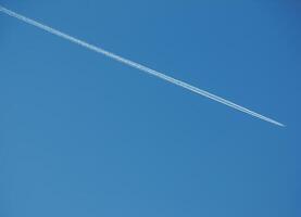 flygplan kondensation spår och flygplan på blå himmel foto