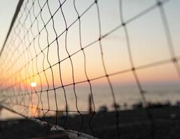 se av de soluppgång genom de volleyboll netto. tidigt morgon- , dramatisk soluppgång över hav vatten foto