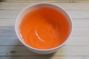 orange gelé i en vit skål och isolerat på en texturerad bakgrund foto