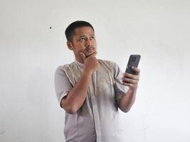 asiatisk man innehav hans mobil telefon med allvarlig uttryck foto