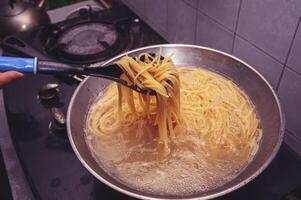 pasta är kokta i kokande vatten i en panorera. foto