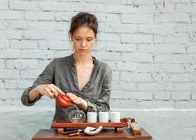 ung kvinna Sammanträde i meditation utgör i främre av te uppsättning och arom pinnar. avslappning begrepp foto