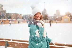 skön härlig medelålders flicka med lockigt hår värma vinter- jackor står is rink bakgrund stad fyrkant. foto