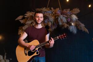 manlig musiker spelar akustisk gitarr. gitarrist spelar klassisk gitarr på skede i konsert foto