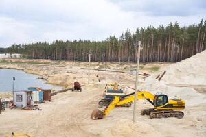 sand stenbrott brytning industri Utrustning grävmaskin traktor stående sand landa nära sjö vatten foto