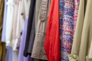 mång färgad Kläder shirts hänga på galgar i en affär bakgrund. en mängd av kläder hängande i de garderob. foto