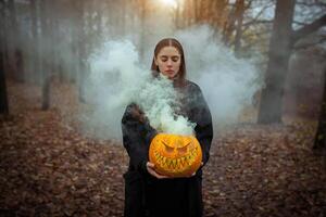 ung kvinna innehav de halloween pumpa med de rök kommande från inuti av den foto
