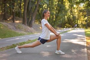 kvinna löpare stretching ben innan utövar sommar parkera morgon- foto