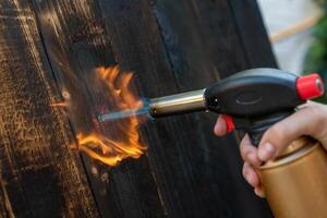 professionell snickare använder sig av gammal traditionell japansk Metod. brinnande trä plankor med gas brännare foto