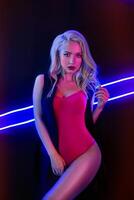 mode konst Foto av elegant modell i förförisk röd baddräkt med ljus neon färgad klubb spotlights natt klubb sexig begrepp