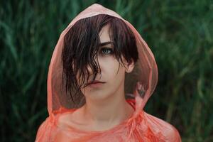 de porträtt av flicka i röd regnkappa under de regn. foto