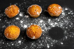 aptitlig muffins stå på en tabell topp se. traditionell bakverk på en mörk bakgrund minimalism. foto