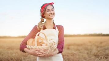 kvinna jordbrukare stående vete jordbruks fält kvinna bagare innehav korg- korg bröd produkt foto