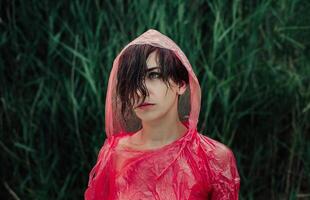 de porträtt av flicka i röd regnkappa under de regn. foto