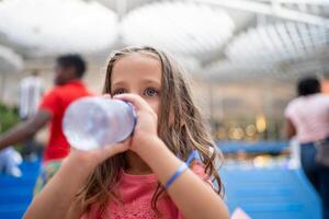 barn dryck vatten från plast flaska utomhus- foto