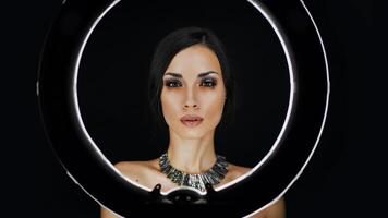 en skön ung caucasian flicka med en skön smink utseende ut från Bakom en cirkulär lampa för porträtt Foto skytte