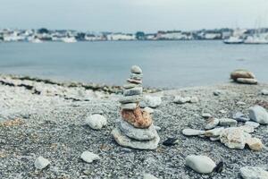 stenar pyramid på sten strand symboliserar stabilitet, zen, harmoni, balans. grund djup av fält. foto