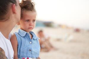 liten flicka gråt mor dotter sommar strand. barn upprörd och gråta foto